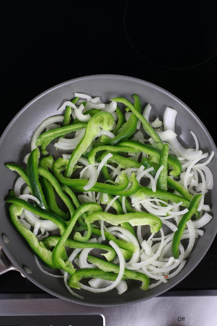 Raw onions and peppers in a pan with olive oil