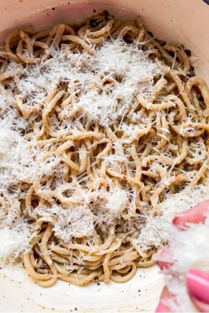 Grated pecorino on top of pasta in a pan.