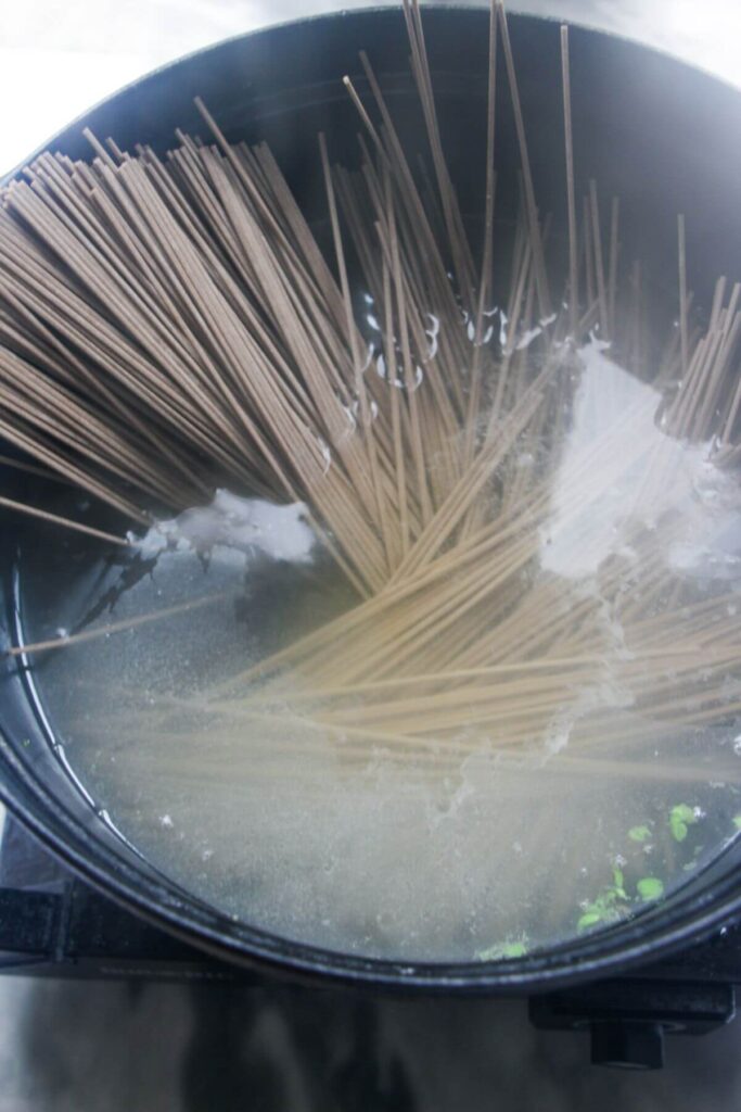Soba noodles cooking in a large pot of water.